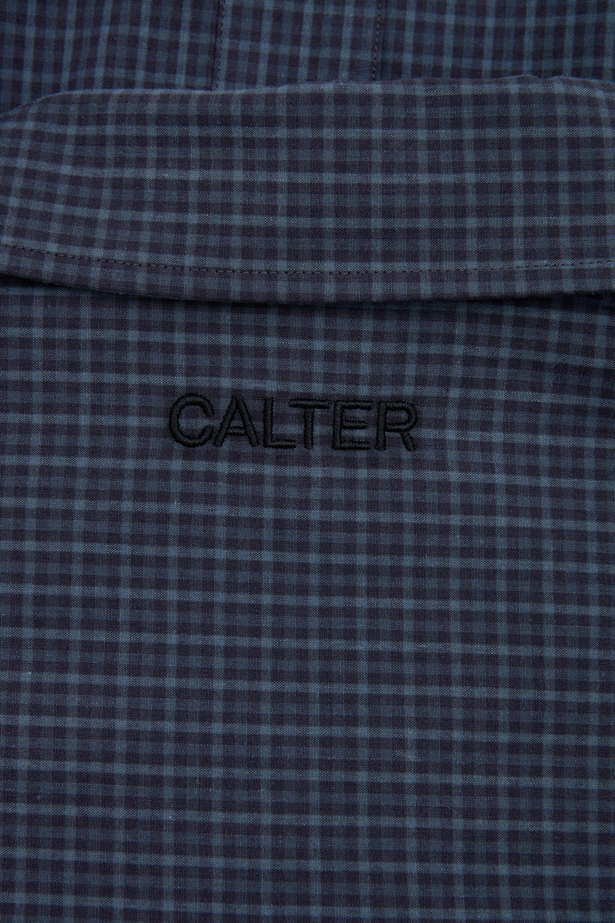 Close-up of the microcheck pattern and black CALTER embroidery on the Slate Microcheck Studio Shirt.