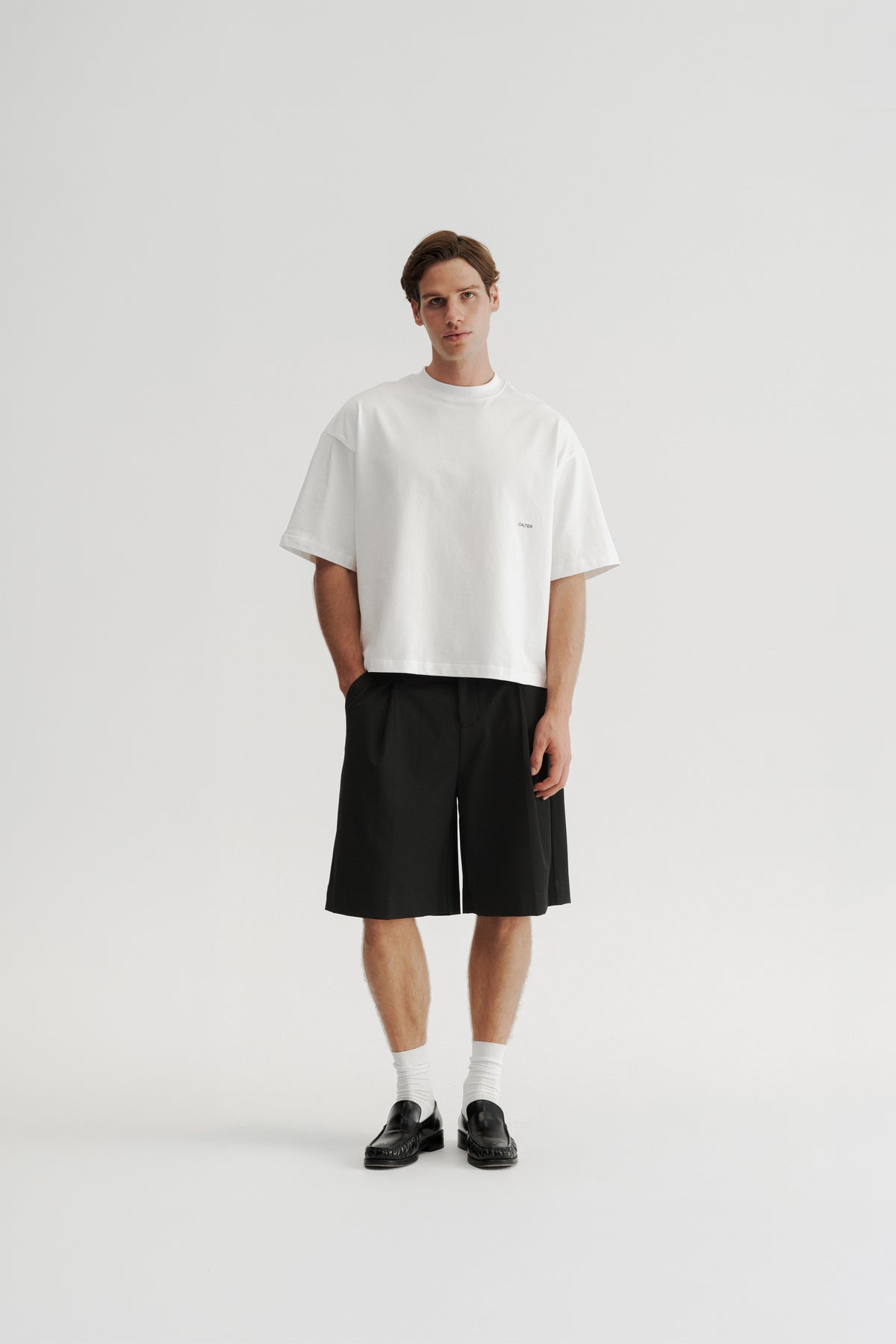 Full-length front view of a model wearing the Off-White Stamp Tee with Black Pleated Shorts.