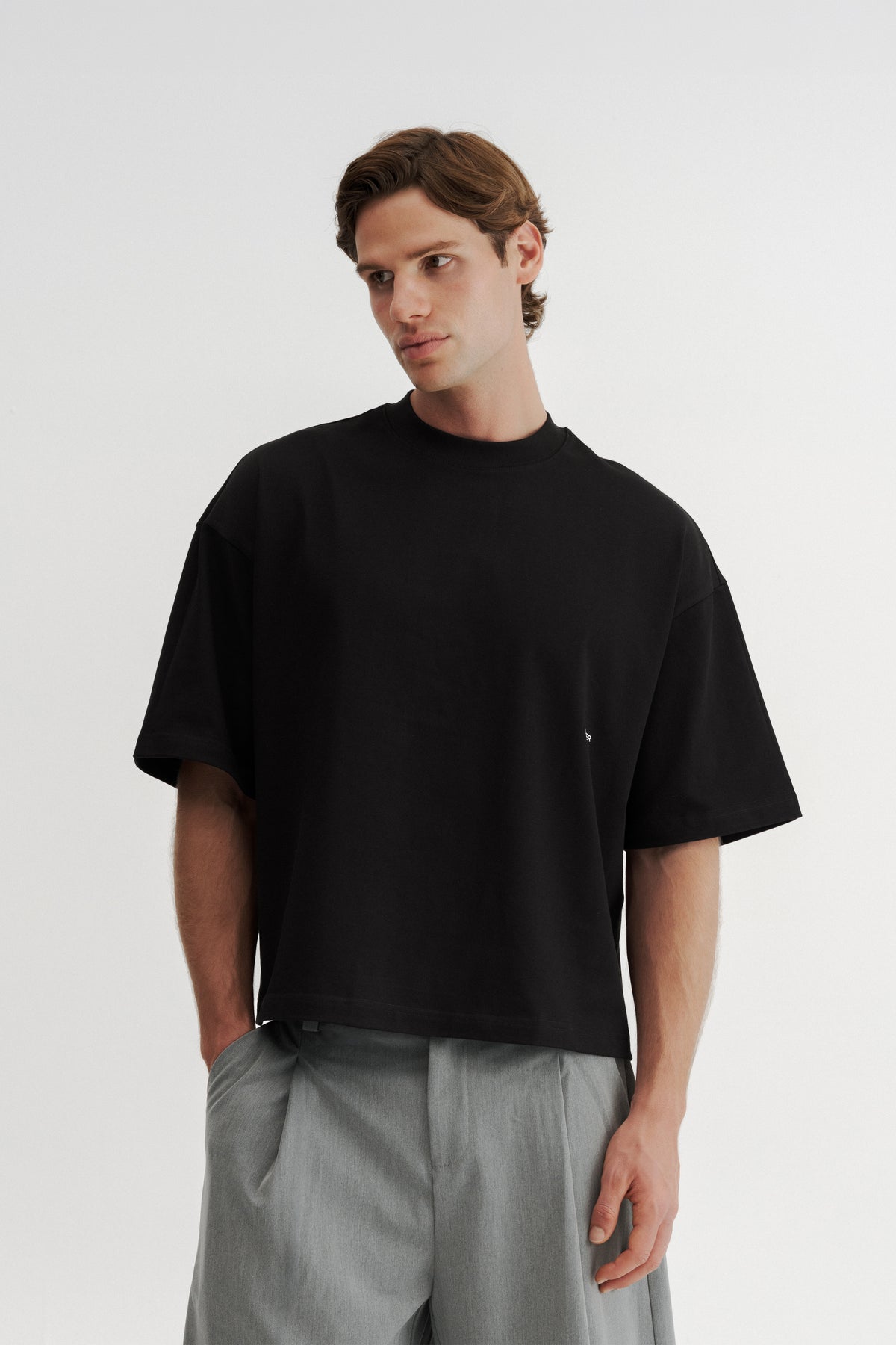 Model wearing the Black Stamp Tee, showing its wide body, dropped shoulders and shortened length.