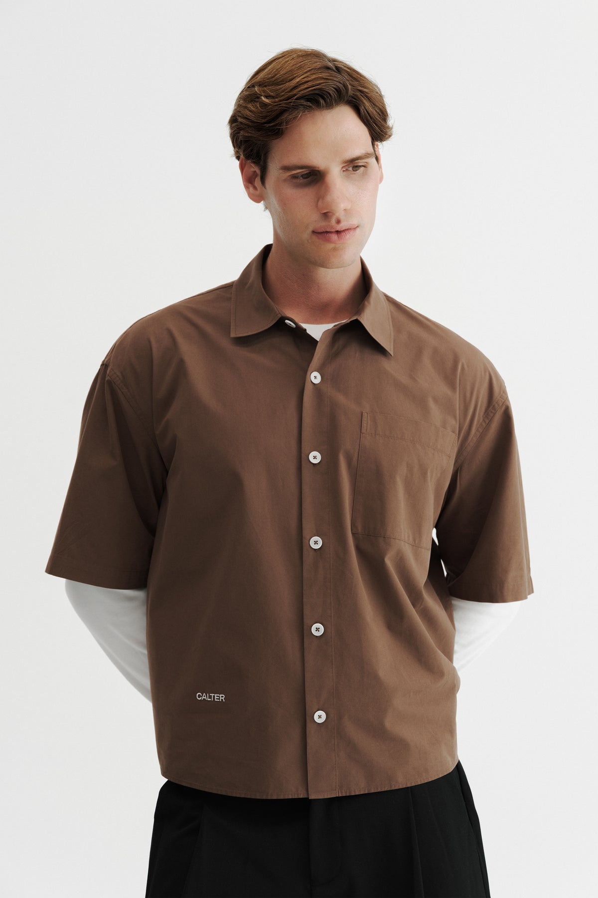 Model wearing the Brown Volume Shirt, showing the short sleeves, chest patch pocket and front-hem embroidery.