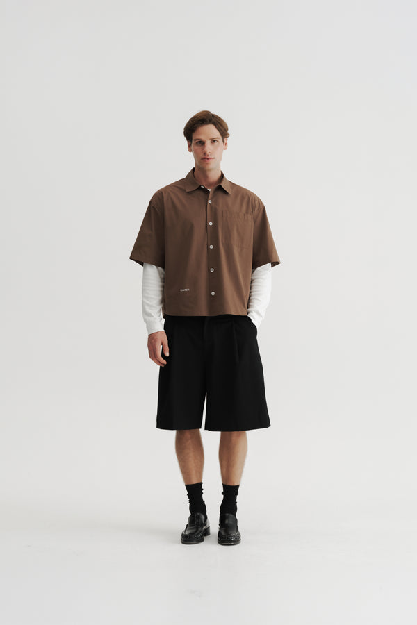 Full-length front view of a model wearing the Brown Volume Shirt over a white long-sleeve top.