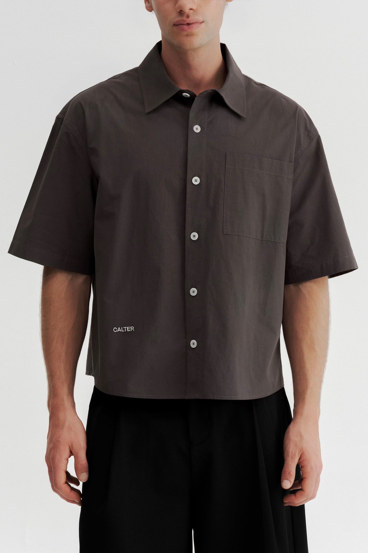 Front view of a model wearing the Charcoal Volume Shirt buttoned, showing the short sleeves and shortened body.